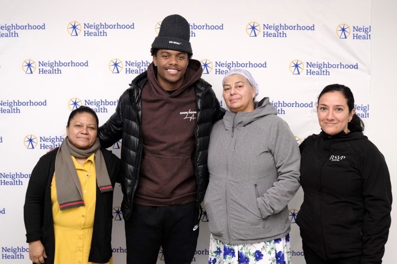 one African American man and three women standing in front of a Neighborhood Health Sign