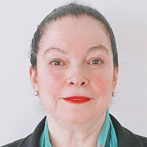 Lillian Perez is a woman with her hair pulled back wearing a teal blouse and black blazer
